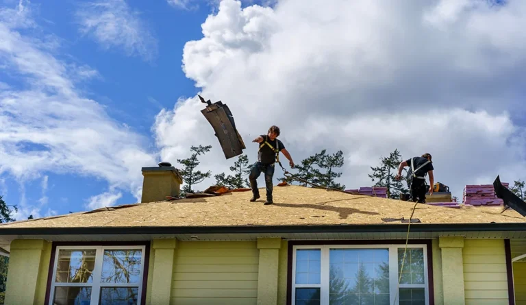 Roofing crew tearing off shingles from residential roof