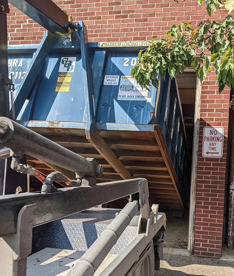 Cobra Roll-Off 15 yard dumpster being backed into a garage.